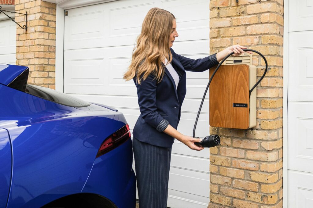 young woman unwinding a bespoke andersen home ev charge point to charge a fully electric jaguar i pace